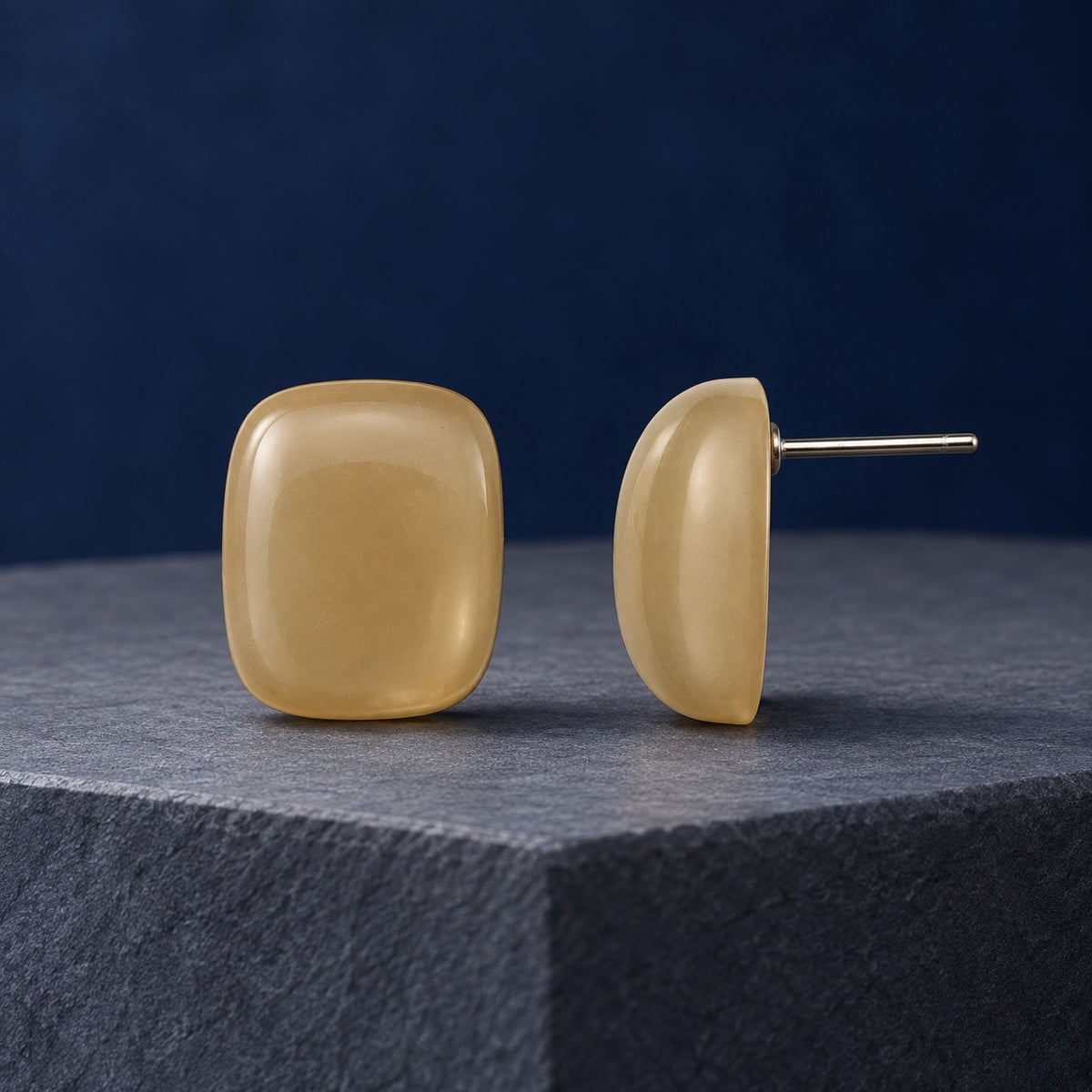 Champagne Cabochon Studs gold-tone rimmed cushion stud earrings on a travertine block