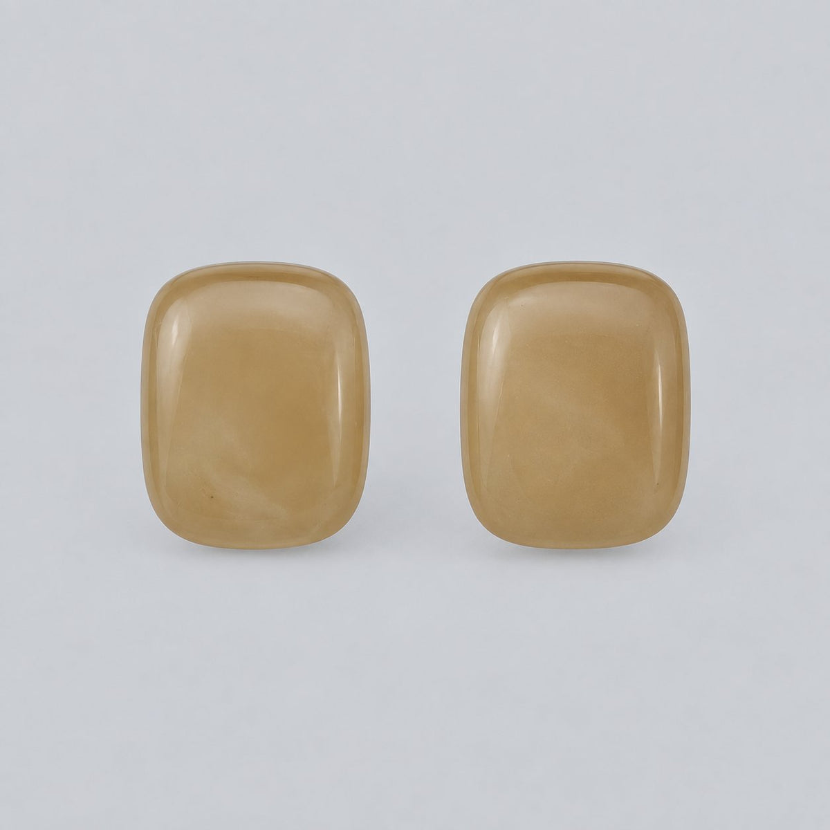 Front view of champagne cushion cabochon stud earrings with gold-tone rim