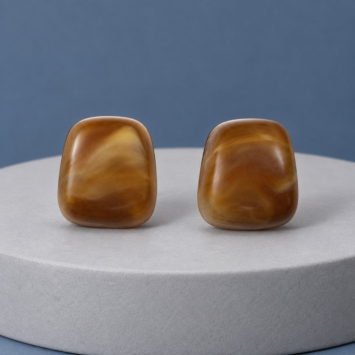 Cognac Cabochon Studs amber cushion stud earrings with silver-tone posts on a travertine block
