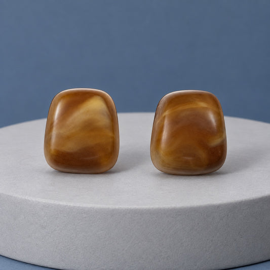 Cognac Cabochon Studs amber cushion stud earrings with silver-tone posts on a travertine block