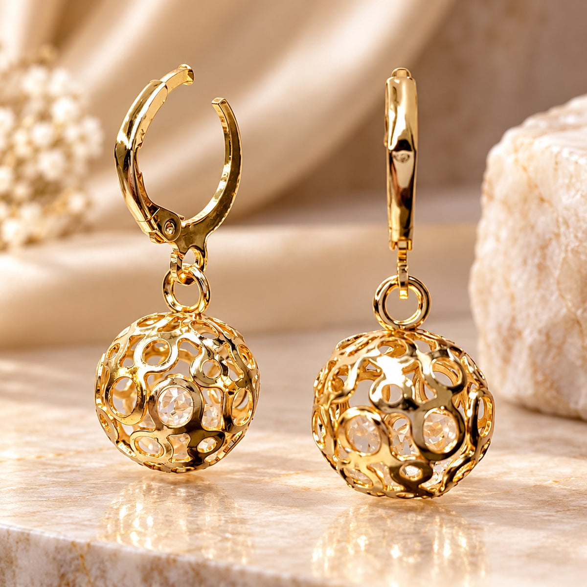 Gilded Filigree Orb Huggie Drops gold-tone filigree orb huggie drop earrings styled on cream marble