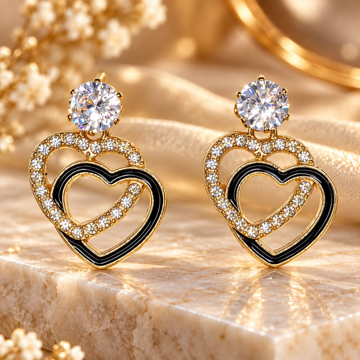 Gilded Noir Heart Drops gold-tone heart drop earrings styled on cream marble