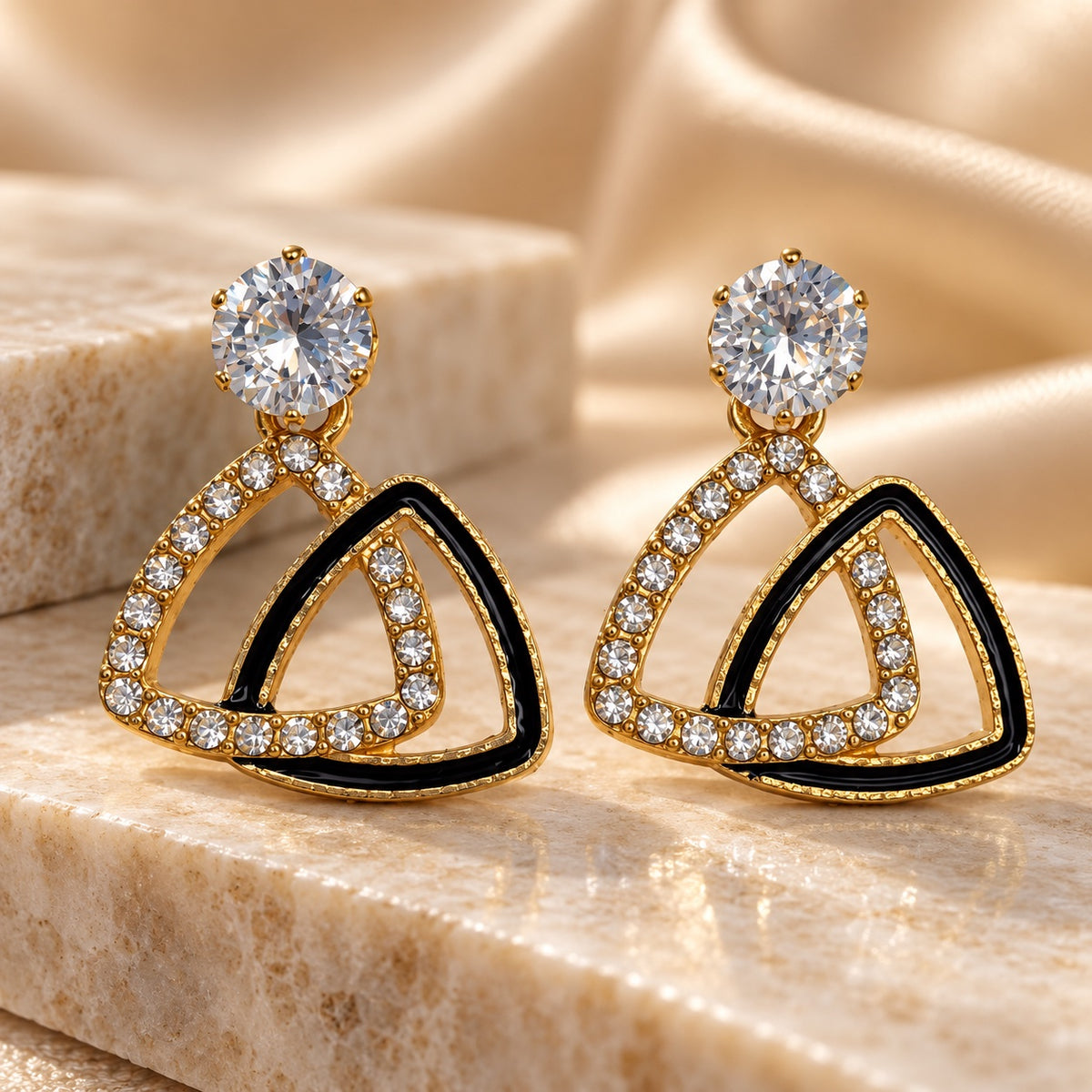 Gilded Noir Trillion Drops gold-tone trillion drop earrings styled on cream marble