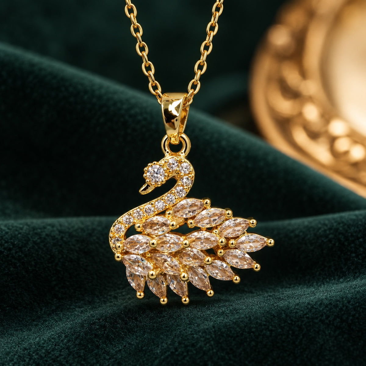 Gilded Swan Pavé Pendant gold-tone necklace with marquise cubic zirconia wings on a dark green velvet backdrop