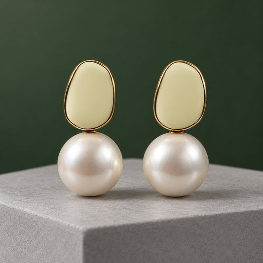 Ivory Enamel Pearl Drop Earrings with an ivory enamel top and large faux pearl on a marble ledge