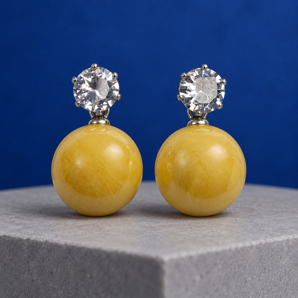 Marigold Yellow Lustre Orb Drop Earrings with sparkling stone tops and yellow orbs on a marble plinth