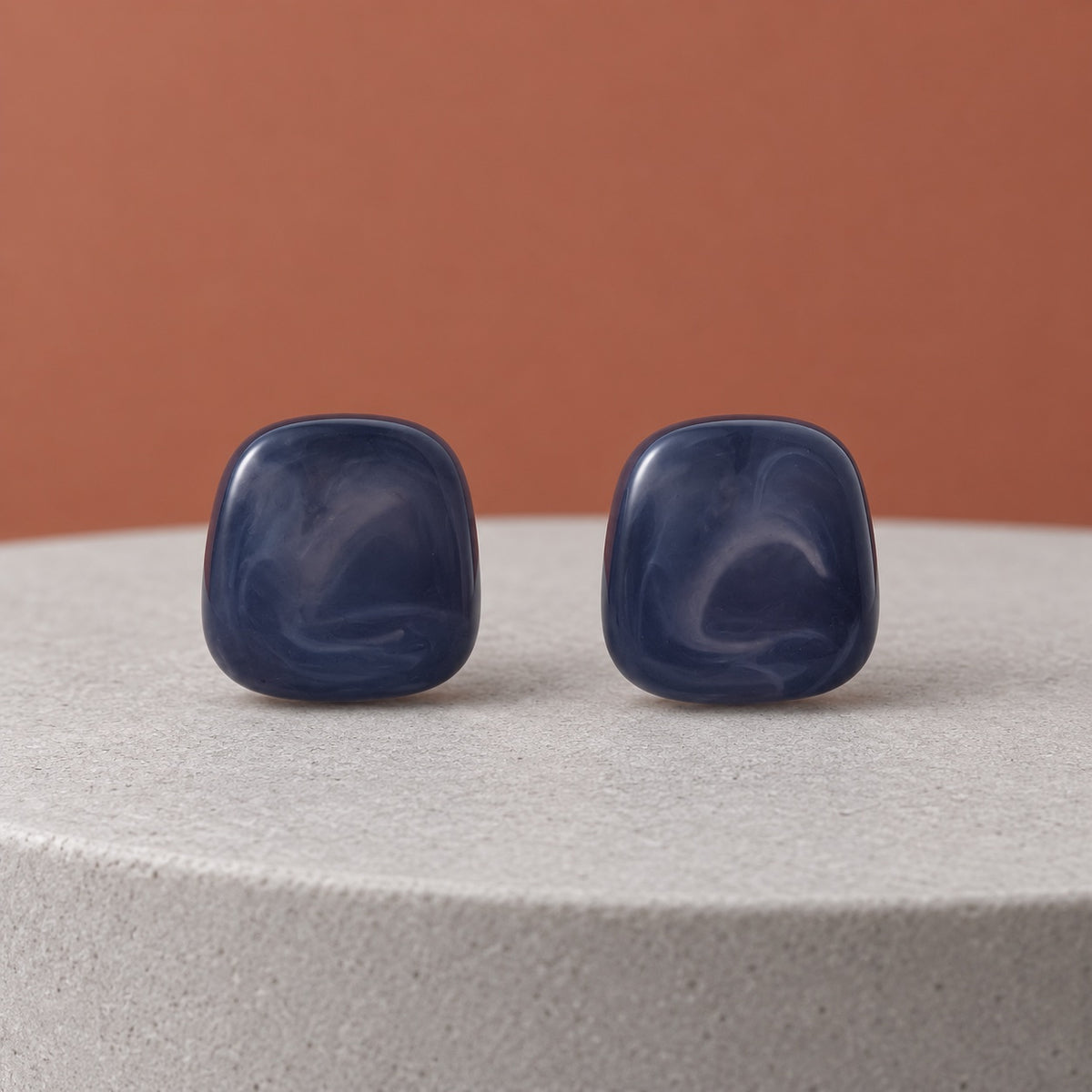 Midnight Blue Cabochon Studs with deep marbled blue stones on a dark marble ledge