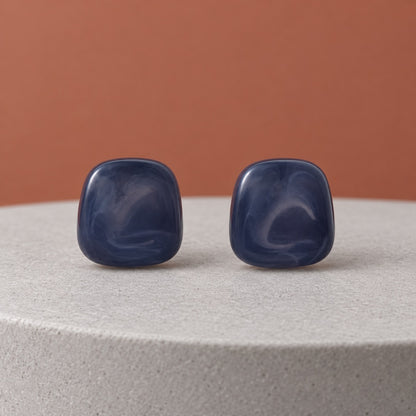 Midnight Blue Cabochon Studs with deep marbled blue stones on a dark marble ledge