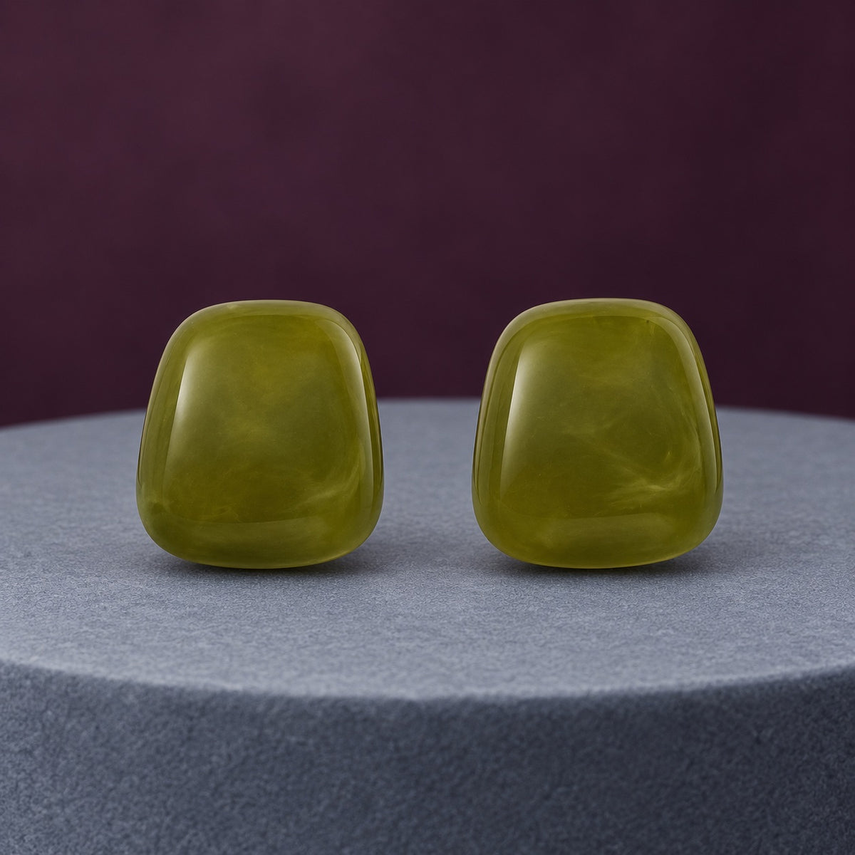 Moss Green Cabochon Studs with glossy jade-like green stones on a travertine ledge
