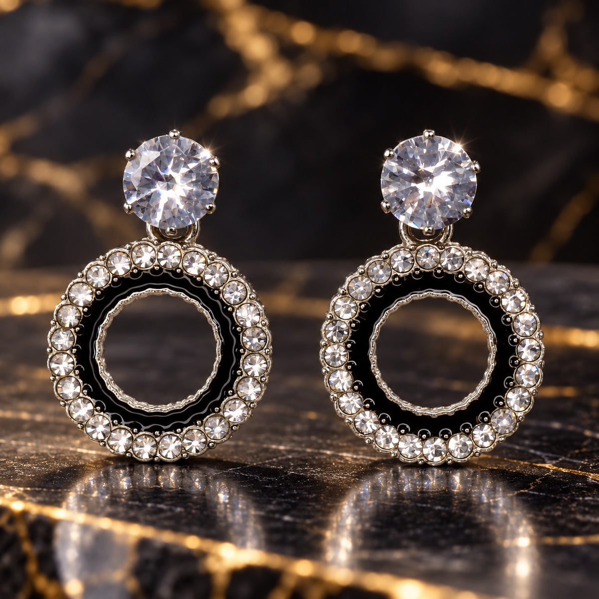 Noir Orbit Halo Drops with sparkling stone tops and black enamel round halos on a marble surface