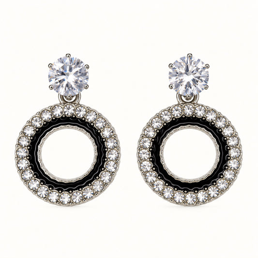 Front view of the silver-tone Noir orbit halo drop earrings with black enamel and crystal edge