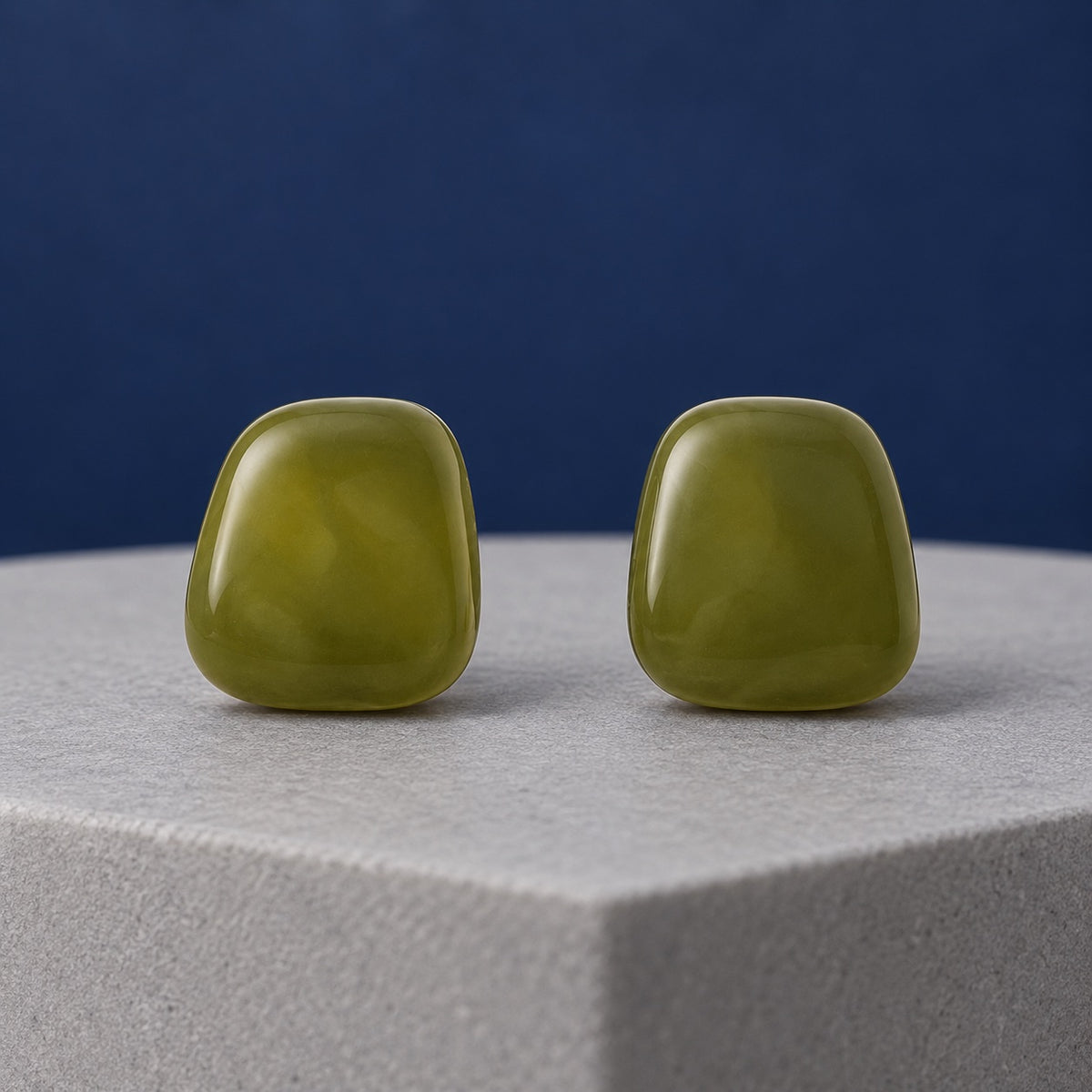 Olive Grove Cabochon Stud Earrings in glossy marbled olive green on a stone ledge