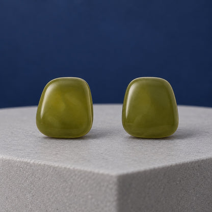 Olive Grove Cabochon Stud Earrings in glossy marbled olive green on a stone ledge