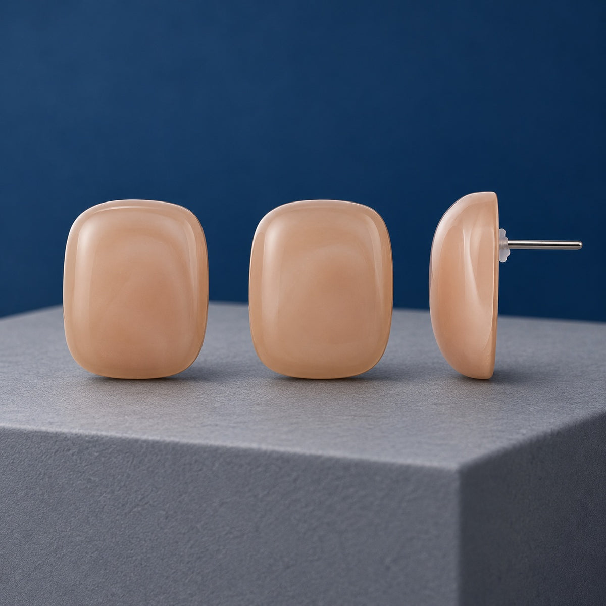 Peach Blush Cabochon Stud Earrings in glossy peach on a cream stone ledge