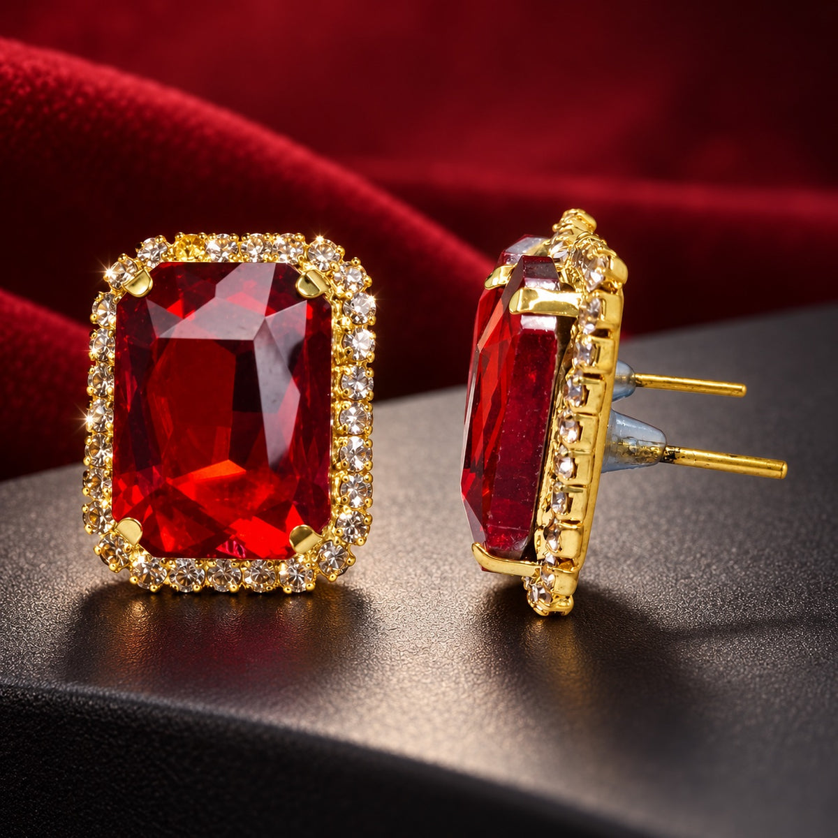 Regal Ruby Red Halo Studs gold-tone earrings with a faceted ruby red centre stone and sparkling halo on a styled surface