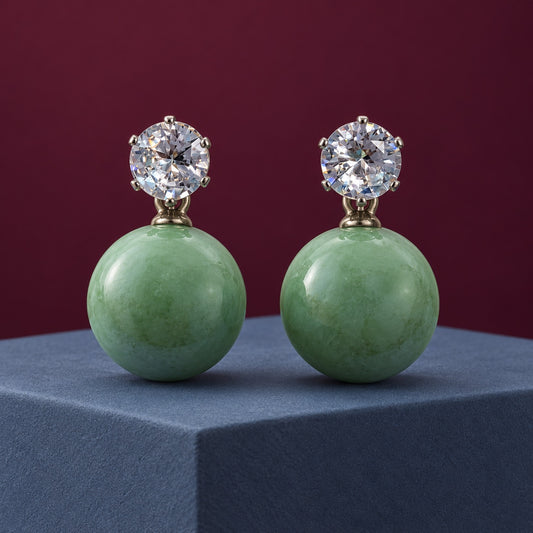 Sage Green Lustre Orb Drops silver-tone earrings with sparkling top stones and glossy sage green orbs on a blue pedestal