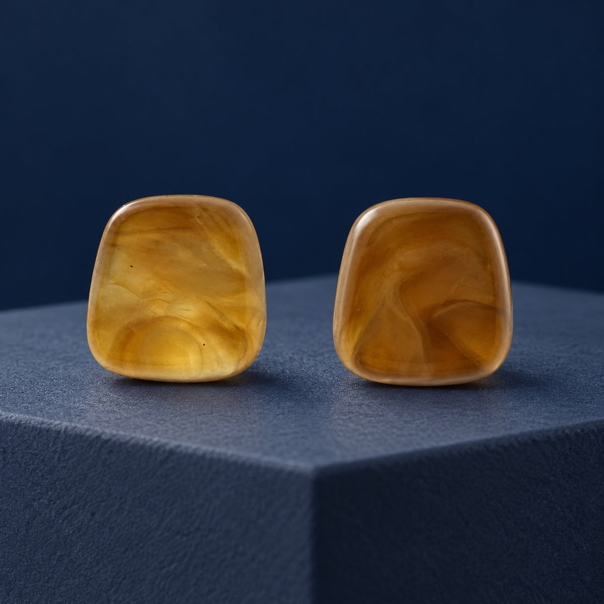 Sunlit Amber Cabochon Studs glowing amber cushion stud earrings on a navy block