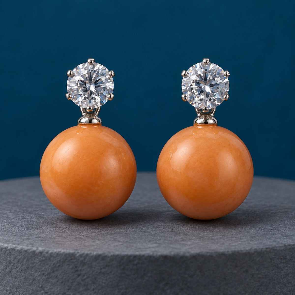 Tangerine Lustre Orb Drops silver-tone earrings with sparkling top stones and glossy tangerine orbs on a grey pedestal
