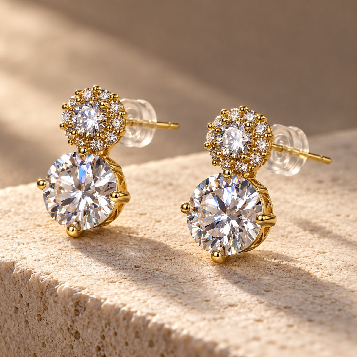Twin Solitaire CZ Studs gold-tone earrings with a large round stone and halo top on a sandstone block